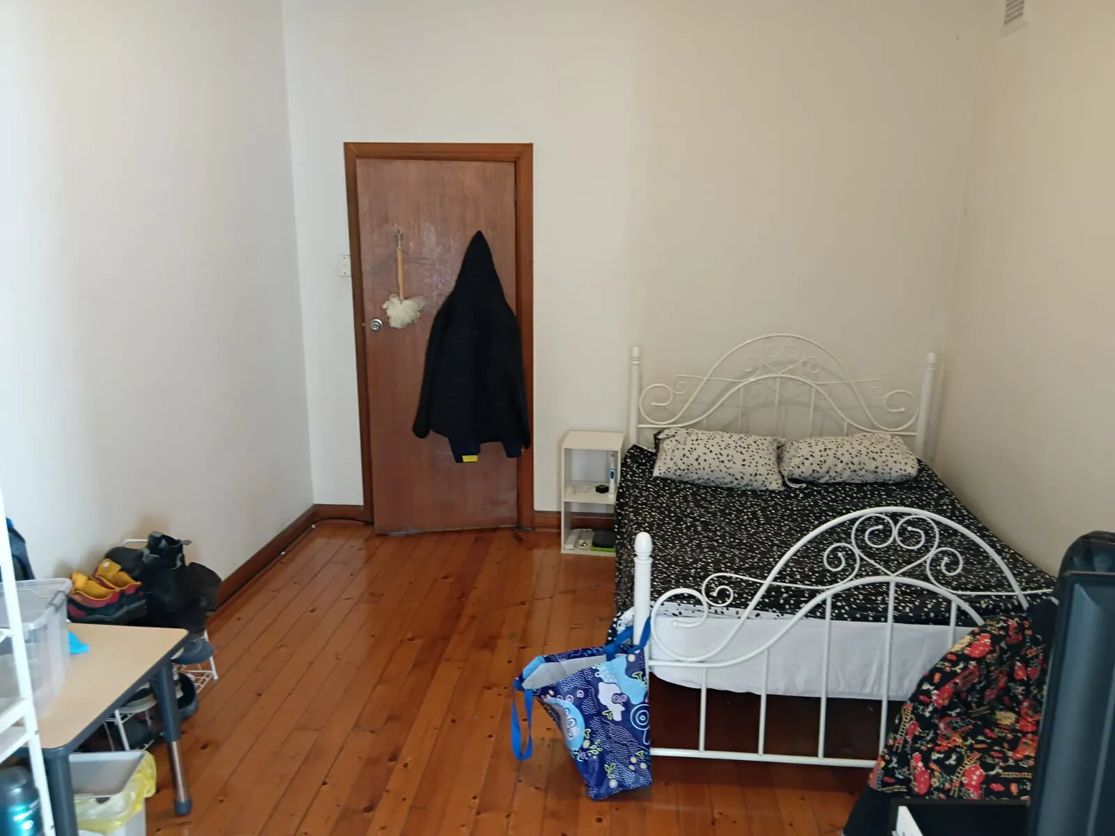 A bedroom at Mascot House with a white metal bed frame and polished timber floors.