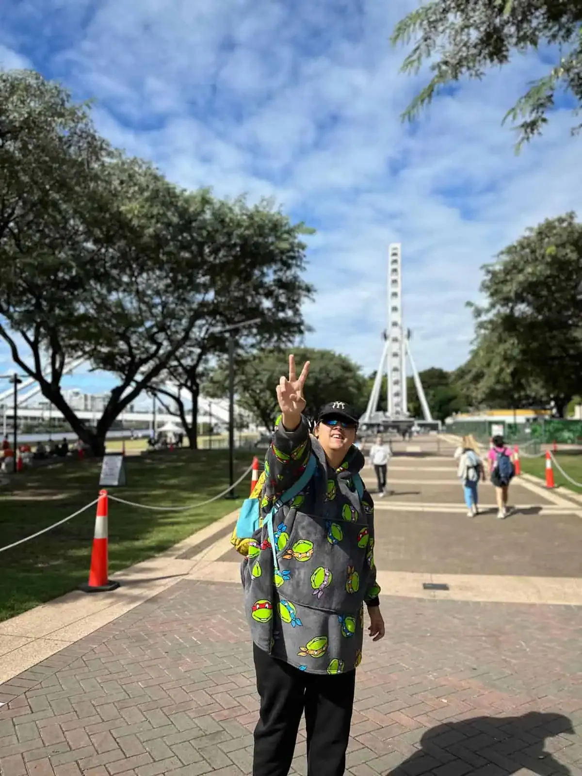 A participant flashing a peace sign in front of the Brisbane wheel.