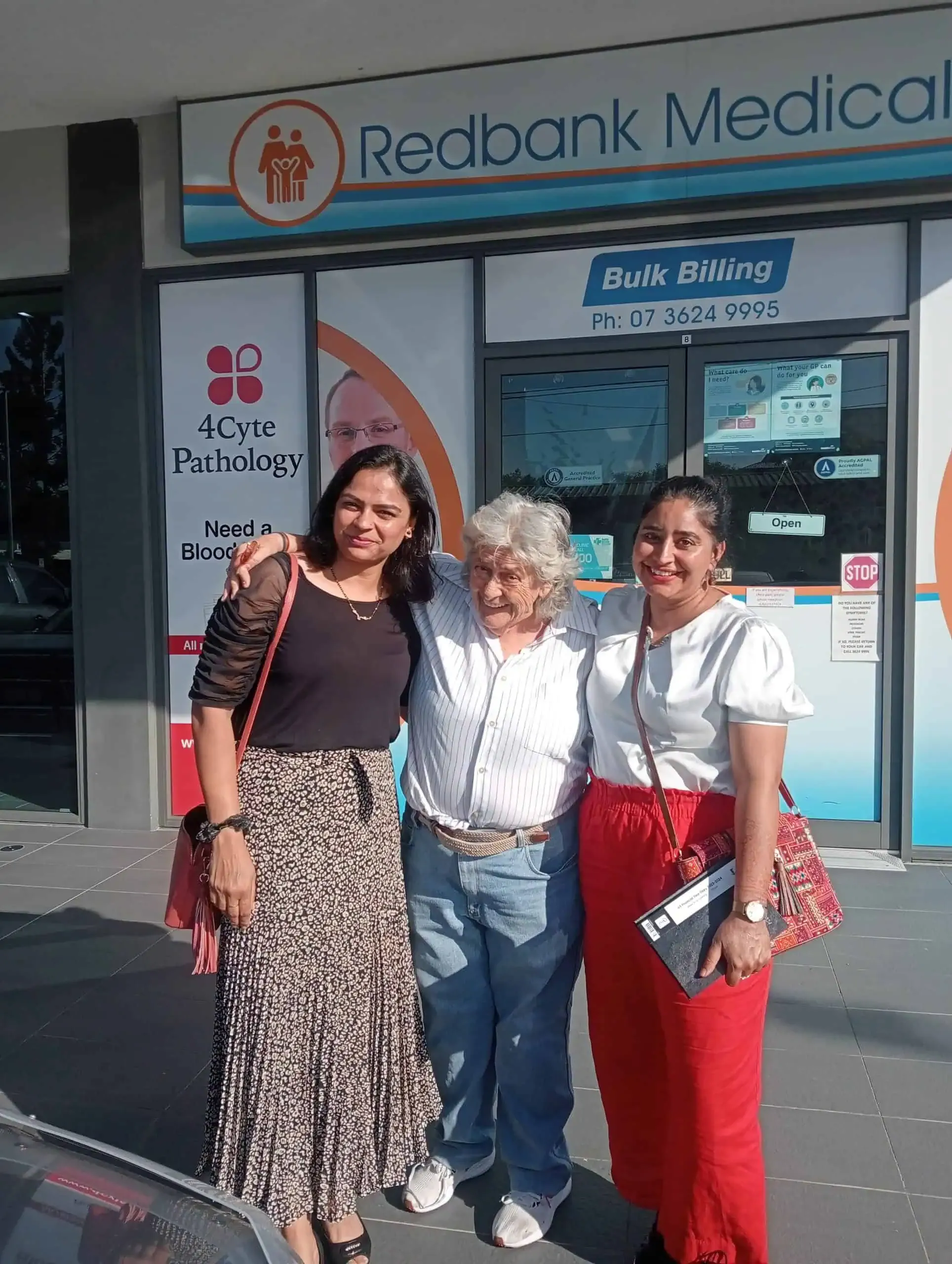 Two support workers with a participant outside a local medical centre.