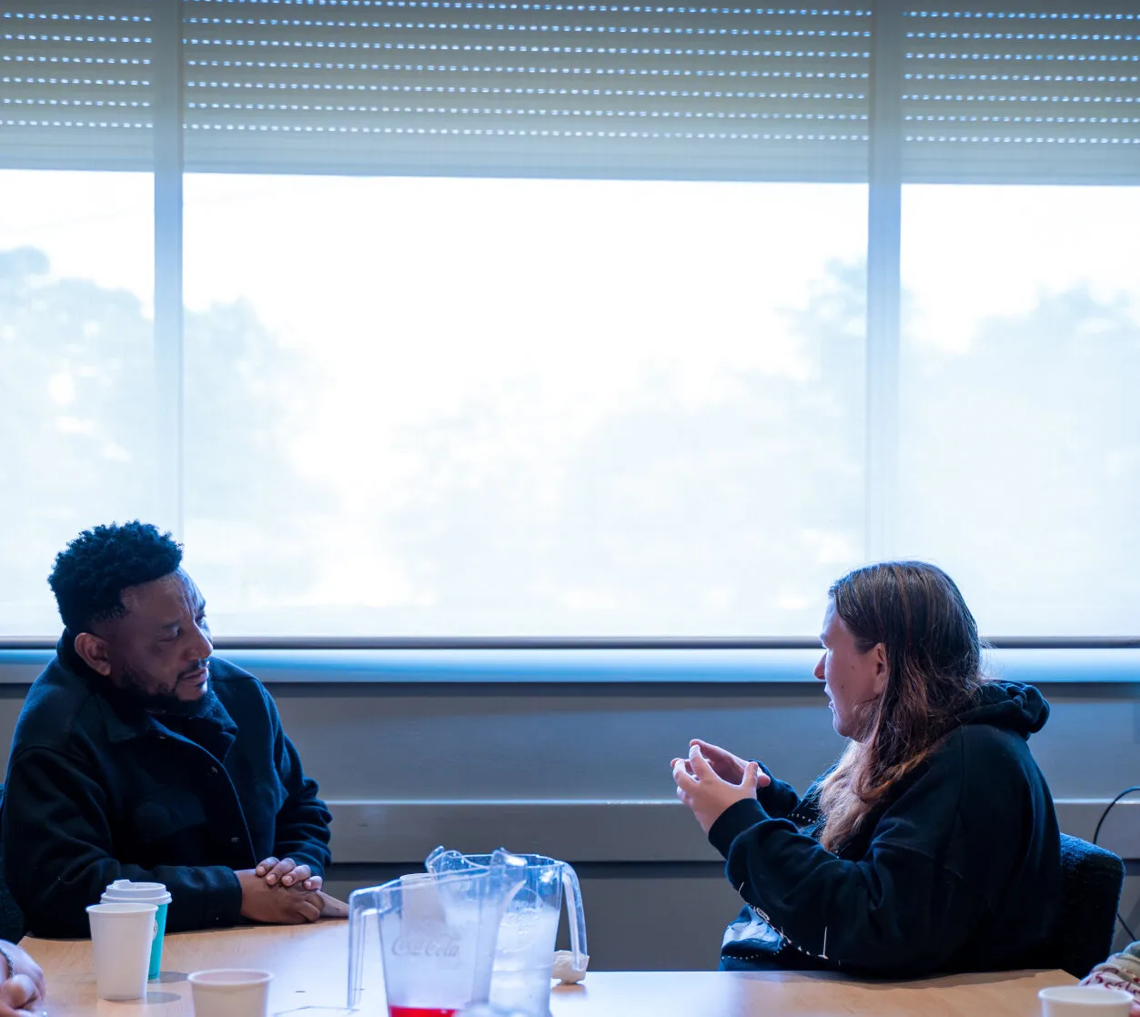 Two people talking things through together at a meeting table.
